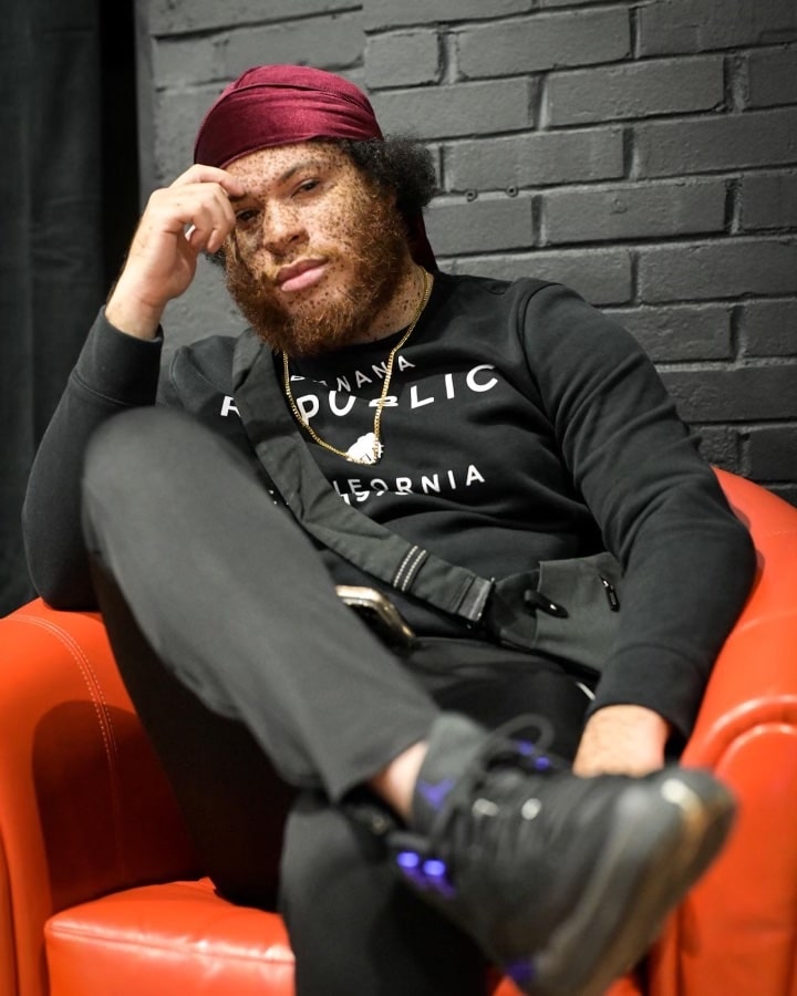 A portrait of Keno Suede sitting on a chair. 